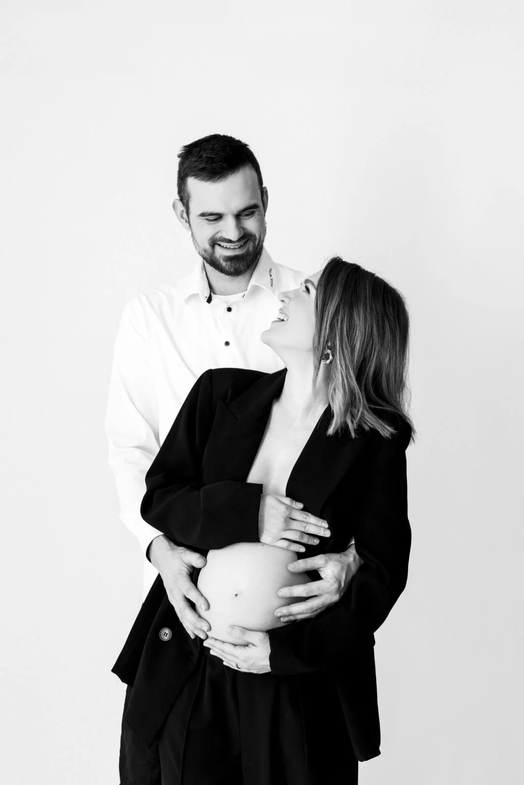 V objemu ljubezni: čarobna črno-bela fotografija nosečniškega para v našem fotografskem studiu v Ljubljani