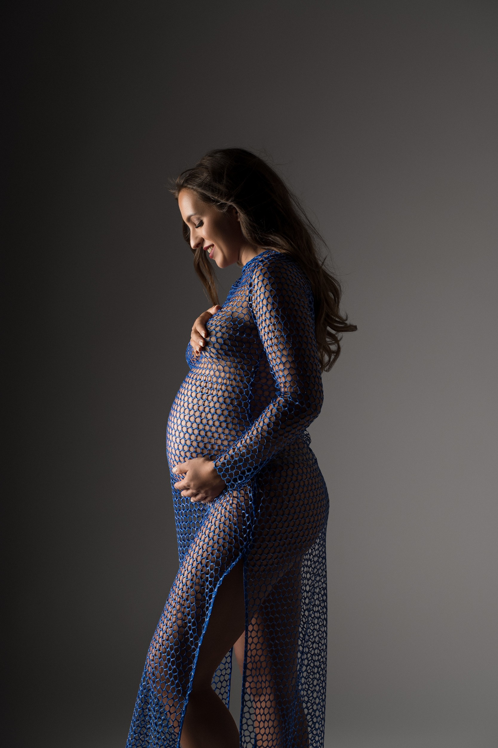 Stilno fotografiranje nosečnice v foto studiu na temnem ozadju