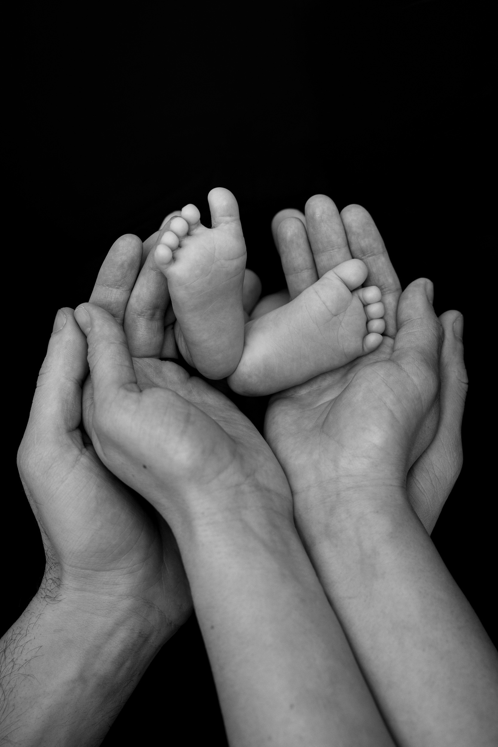 Fotografiranje novorojenčka v studiu ali doma: noge novorojenčka in roke starših