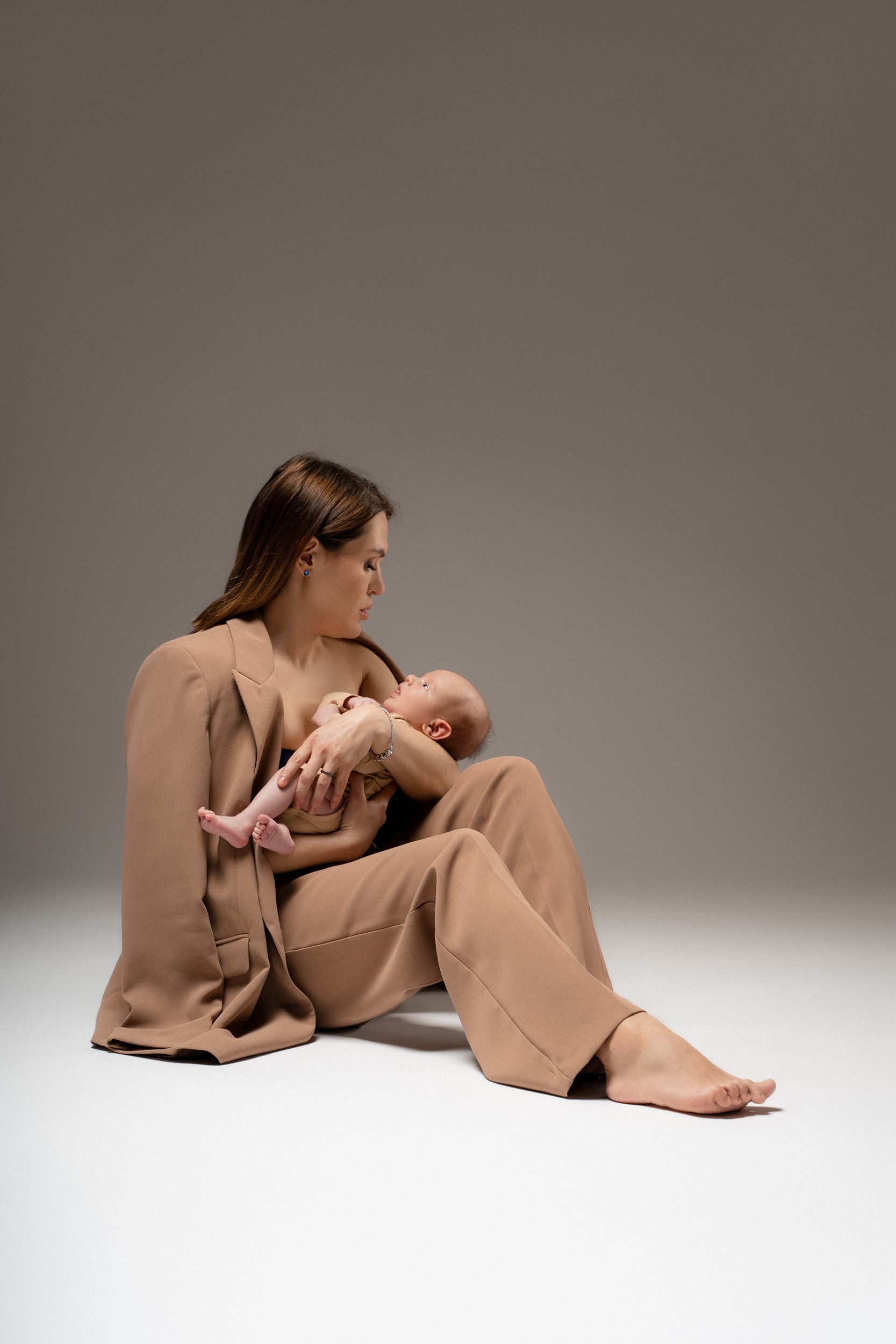 Mama drži novorojenčka na studijskem fotografiranju
